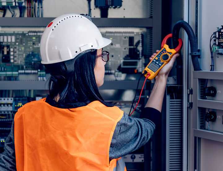 About Us page features confident woman in orange vest and hard hat with multimeter