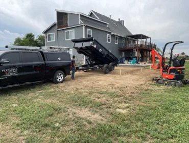 A black truck and a dump truck parked in front of a house. Image represents our electrical solutions for our work page